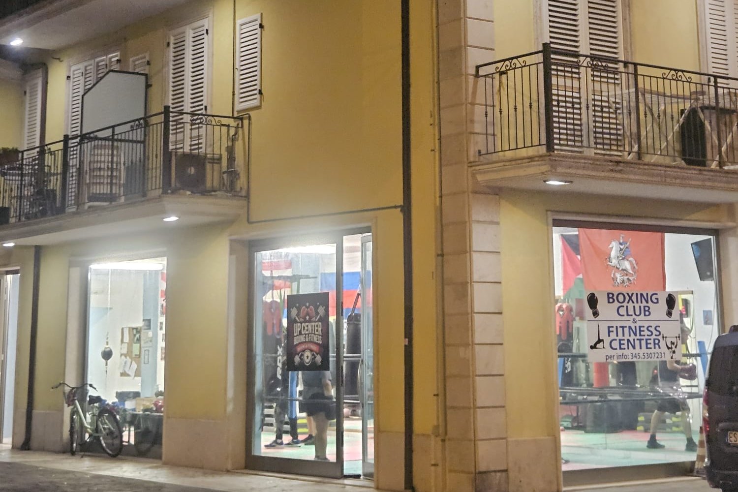 L'ingresso di Up Center in via Fratelli Rosselli 85, di sera, con le vetrine illuminate e l'insegna Boxing Club e Fitness Center